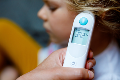 Thermometer reading 39.3*C is held in front of little girl