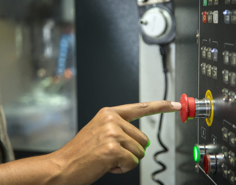 finger pressing red button on a machine